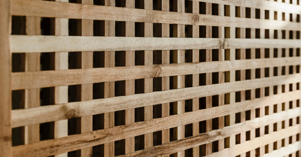 A wooden lattice screen with a smooth, warm finish. The wood is natural with multiple knots visible in the grain.