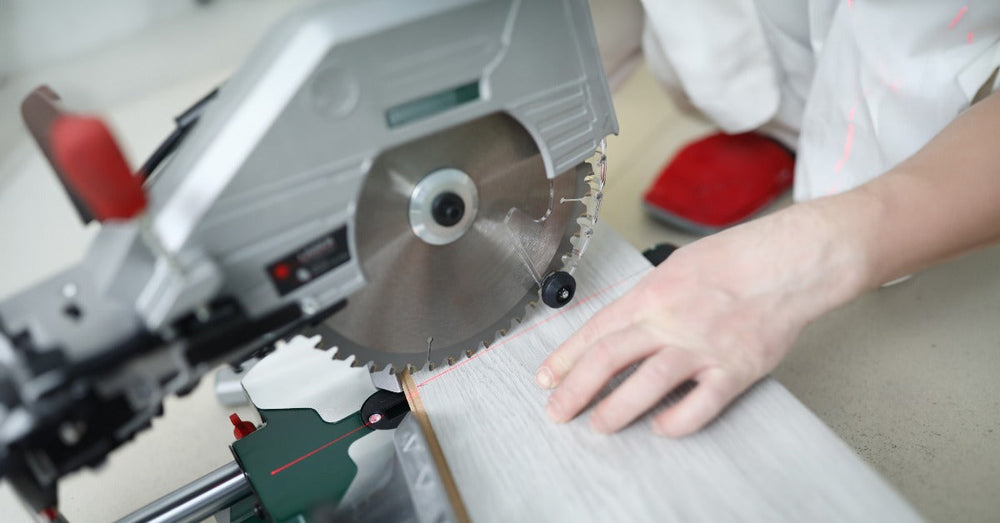A man using a circular saw table to cut through a plank of wood. The blade isn't spinning yet as he lines it up.